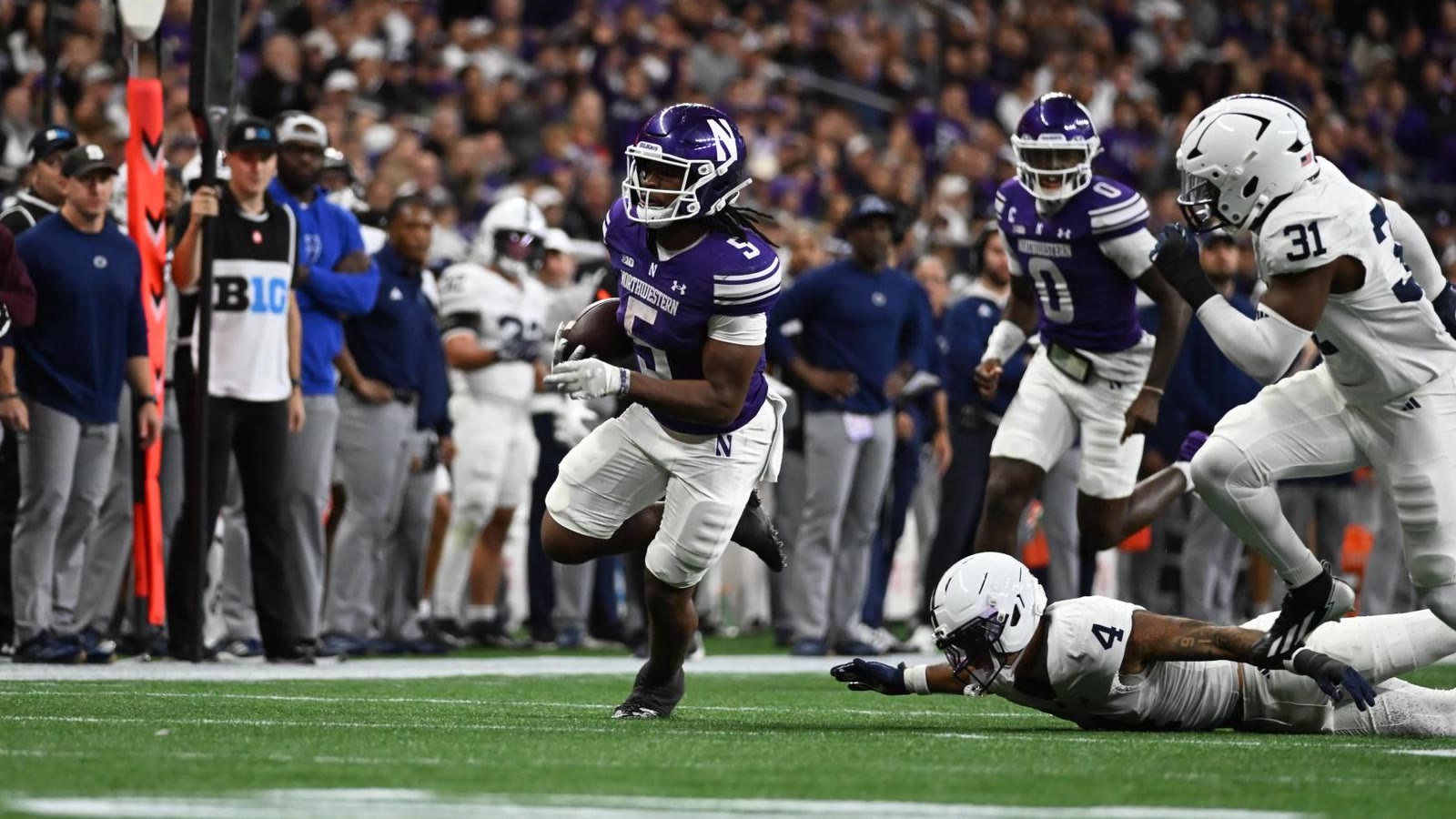 Northwestern running back Caleb Komolafe runs past Penn State defenders